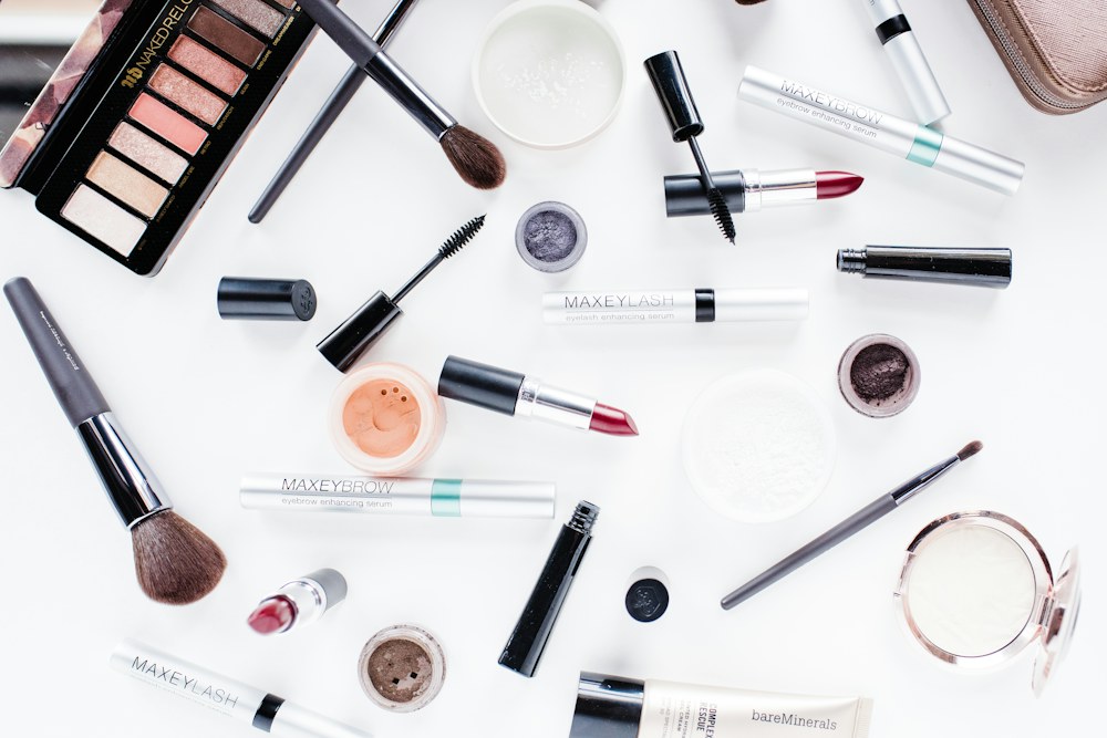 Makeup products and brushes arranged on a white surface