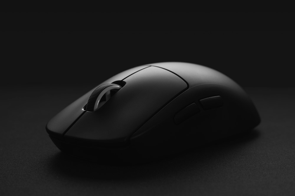 black cordless computer mouse on black surface; illustrative stock photograph