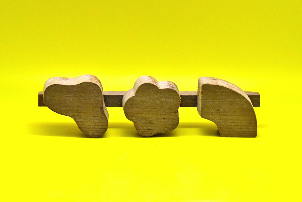 three wooden elephants on a yellow background; illustrative stock photograph