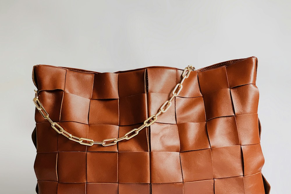 brown leather handbag on white surface; illustrative stock photograph