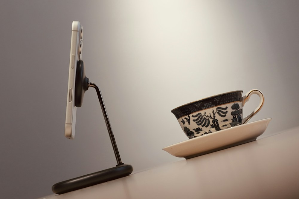 Smartphone on stand next to teacup and saucer; illustrative stock photograph