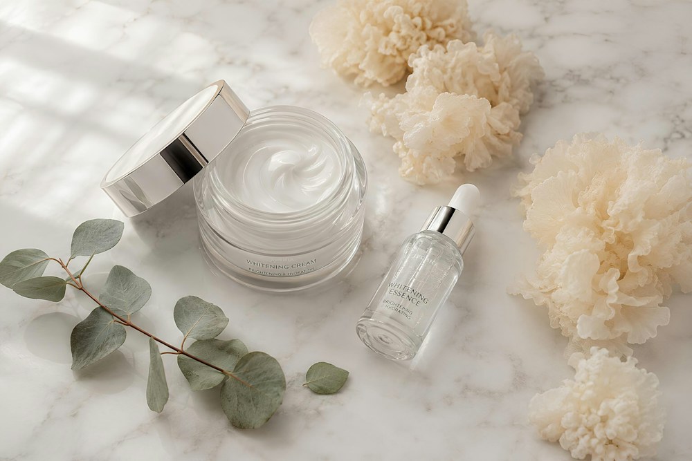 Skincare cream, serum, eucalyptus, and fluffy elements on marble; illustrative stock photograph