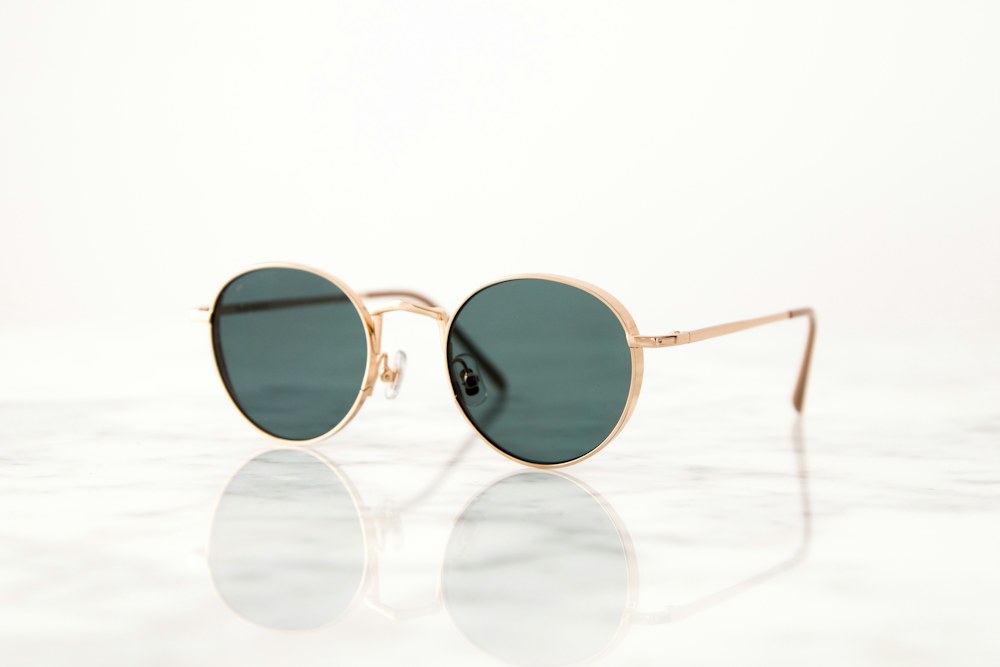 gold-colored framed hippie sunglasses on white surface; illustrative stock photograph