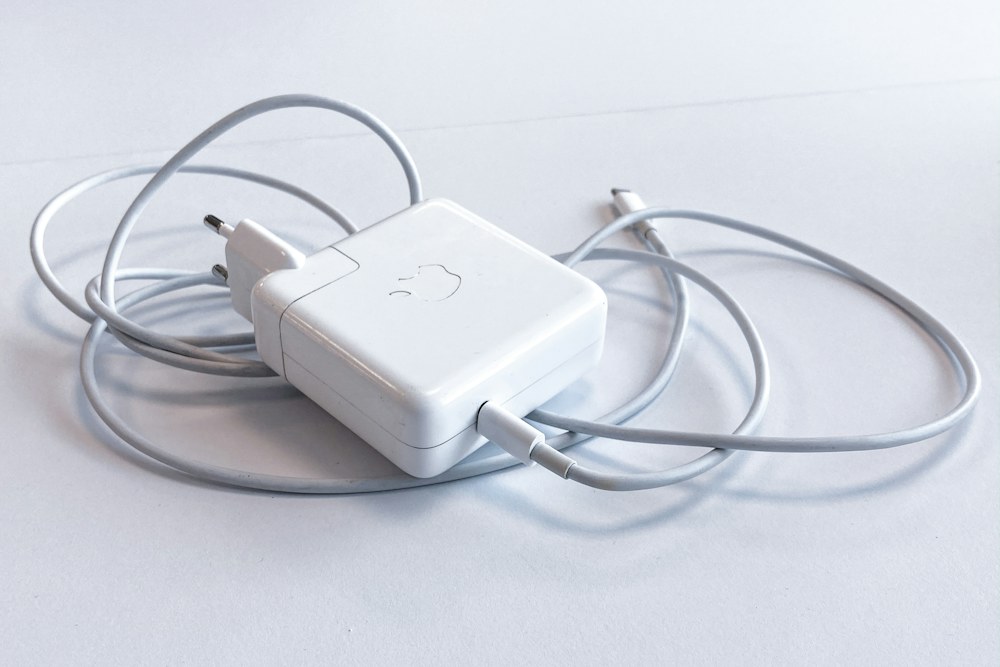 white apple charging adapter on white table; illustrative stock photograph